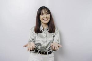 Young Asian woman wearing sage green shirt presenting an idea while looking smiling on isolated white background photo