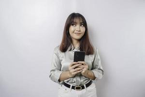 Photo of a thoughtful young woman holding her phone and looking aside. isolated on white color background