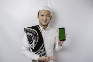 un retrato de un musulmán asiático feliz sonriendo mientras muestra espacio de copia en su teléfono, aislado por fondo blanco foto