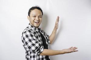 Excited Asian man wearing tartan shirt is pointing at the copy space beside him, isolated by white background photo