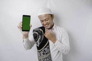 Portrait of a peaceful Asian Muslim man is showing copy space on his phone and smiling feel relief photo