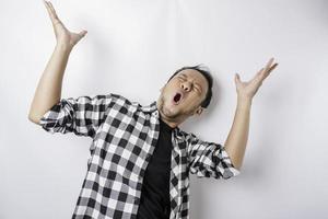 Shocked Asian man wearing tartan shirt pointing at the copy space on top of him, isolated by a white background photo