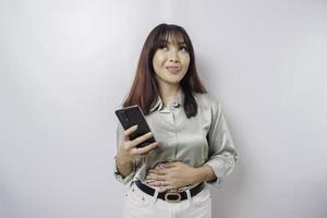 Photo of a hungry excited young woman holding her phone and wondering what to order yummy food isolated on white color background