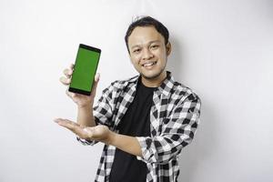 un retrato de un hombre asiático feliz sonríe mientras muestra espacio de copia en su teléfono, aislado por fondo blanco foto