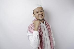 Excited Asian Muslim man pointing at the copy space beside him, isolated by white background photo