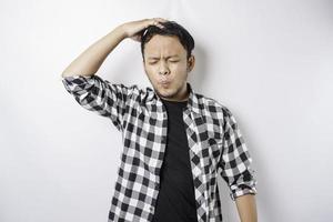 A portrait of a stressed Asian man wearing a tartan shirt isolated by white background looks depressed photo