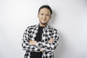 Portrait of a confident smiling Asian man wearing tartan shirt standing with arms folded and looking at the camera isolated over white background photo
