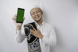 Portrait of a peaceful Asian Muslim man is showing copy space on his phone and smiling feel relief photo