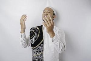 Happy handsome Asian Muslim man with prayer rug on his shoulder is praying to God. photo