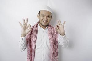 Excited Asian Muslim man giving an OK hand gesture isolated by a white background photo