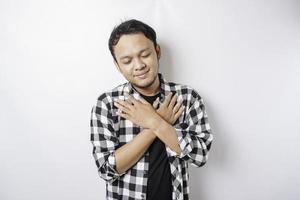 Portrait of a peaceful Asian man wearing tartan shirt is smiling and feel relief photo