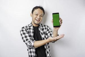 un retrato de un hombre asiático feliz sonríe mientras muestra espacio de copia en su teléfono, aislado por fondo blanco foto