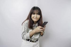 A dissatisfied young Asian woman looks disgruntled wearing sage green shirt irritated face expressions holding her phone photo