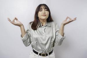 Portrait of a casual pretty woman meditating on white background. Stress free relief at work concept, peaceful young woman practicing breathing yoga exercise photo