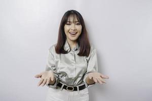 Young Asian woman wearing sage green shirt presenting an idea while looking smiling on isolated white background photo