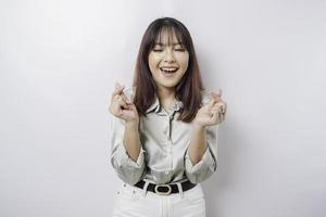 An attractive young Asian woman wearing a sage green shirt feels happy and a romantic shapes heart gesture expresses tender feelings photo