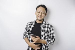 Photo of a hungry excited young man holding his phone and wondering what to order yummy food isolated on white color background