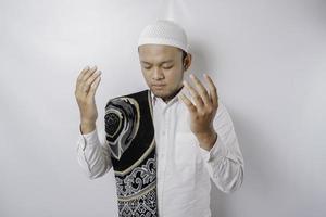 Happy handsome Asian Muslim man with prayer rug on his shoulder is praying to God. photo