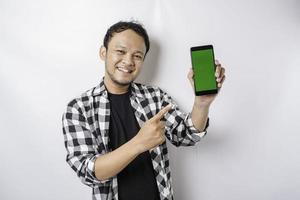 un retrato de un hombre asiático feliz sonríe mientras muestra espacio de copia en su teléfono, aislado por fondo blanco foto