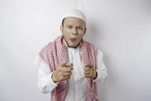 Young Asian Muslim man standing over isolated white background pointing fingers to camera with happy face. Good energy and vibes. photo