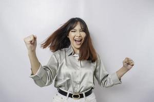 una joven asiática con una expresión feliz y exitosa que usa una camisa verde salvia aislada de fondo blanco foto