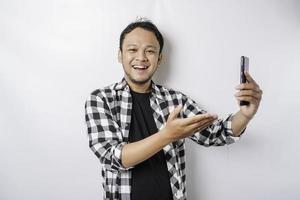 A portrait of a happy Asian man is smiling while holding on his phone, isolated by white background photo