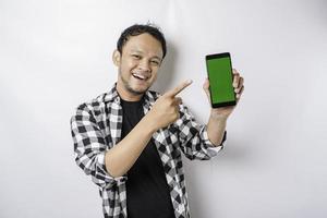 A portrait of a happy Asian man is smiling while showing copy space on his phone, isolated by white background photo