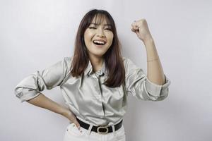 A young Asian woman with a happy successful expression wearing sage green shirt isolated by white background photo