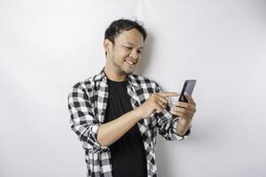 un retrato de un hombre asiático feliz sonríe mientras sostiene su teléfono, aislado por fondo blanco foto