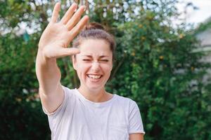 mujer joven sonriendo al aire libre. hermosa chica brunete descansando sobre un fondo verde de parque o jardín. mujer feliz libre en verano. libertad felicidad despreocupada gente feliz concepto. foto