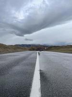 Asphalt road wet after rain goes into the distance, a part of the Chuisky tract, Altai, Russia photo
