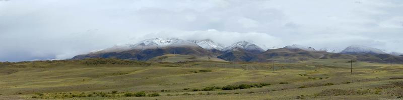 Clouds lying on the tops of snow-capped mountains in the Altai mountains photo