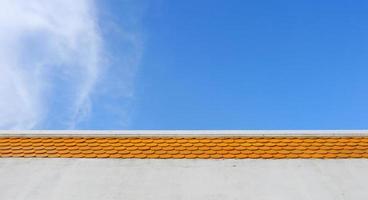 Bright orange color rooftop of building and bright blue sky with cloud. photo