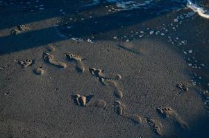 Footsteps in the sand on the beach, sandy beach, sea waves. photo