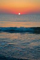 hermosa puesta de sol de verano en la playa, olas y arena foto