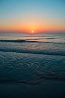 hermosa puesta de sol de verano en la playa, olas y arena foto