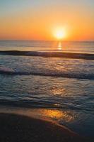 hermosa puesta de sol de verano en la playa, olas y arena foto