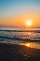 hermosa puesta de sol de verano en la playa, olas y arena foto