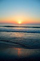 Beautiful summer sunset at the beach, waves and sand photo