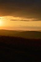 Sunset in nature, orange, sky with clouds, field and woods photo