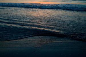 hermosa puesta de sol de verano en la playa, olas y arena foto