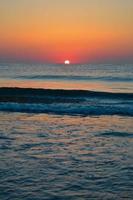 hermosa puesta de sol de verano en la playa, olas y arena foto