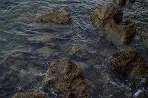 agua de mar clara, rocas en la playa. foto