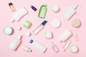 grupo de botellas de plástico para el cuidado del cuerpo composición plana con productos cosméticos sobre fondo rosa espacio vacío para su diseño. conjunto de envases cosméticos blancos, vista superior con espacio de copia foto