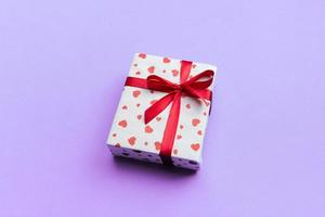 Background with gift box and hearts on purple Background. Top view with copy space for text photo