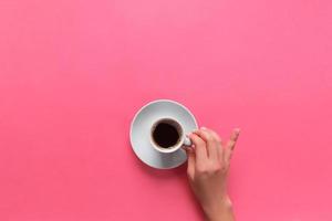 High angle of woman hands holding coffee cup on pink background Minimalistic style. Flat lay, top view isolated photo