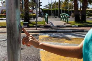 mujer presiona la mujer presiona el botón para el cruce de peatones en los semáforos de la carretera. foto