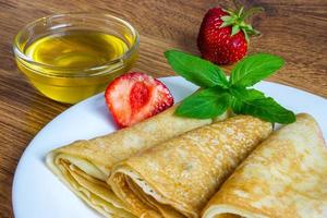 pila de crepes con jarabe de fresa y miel foto