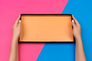 Female hands holding empty present box on pink and blue background photo