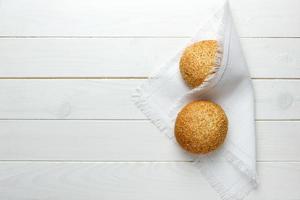 baked bun with sesame seeds lying on fabric photo